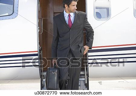 Stock Image - A businessman leaving a plane. Fotosearch