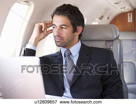 A businessman sitting on a plane View Large Photo Image Stock Photo - A businessman sitting on a plane. Fotosearch