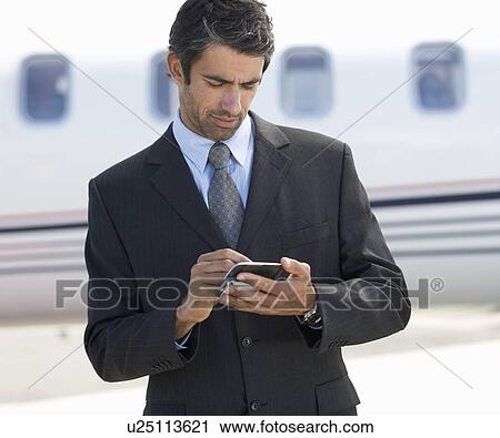 Stock Image - A businessman standing by a plane. Fotosearch