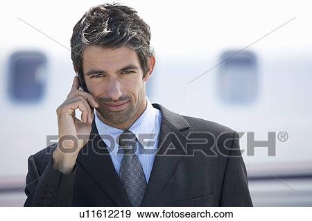 Stock Photo - A businessman standing by a plane. Fotosearch