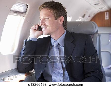 A businessman talking on a mobile phone in a plane View Large Photo Image Stock Image - A businessman talking on a mobile phone in a plane. Fotosearch