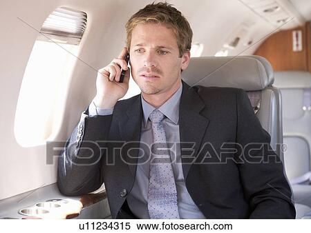 A businessman talking on a mobile phone in a plane View Large Photo Image Stock Photography - A businessman talking on a mobile phone in a plane. Fotosearch