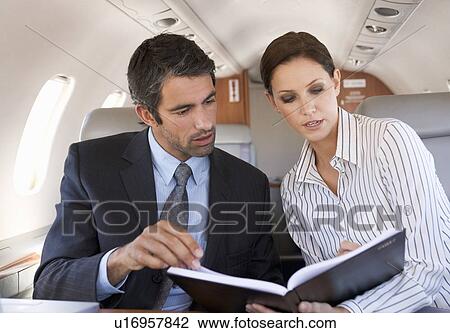 Stock Image - A businessman talking to his PA on a plane. Fotosearch