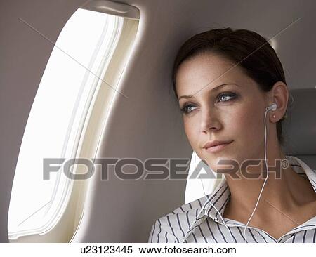 A businesswoman listening to music on a flight View Large Photo Image Stock Photography - A businesswoman listening to music on a flight. Fotosearch