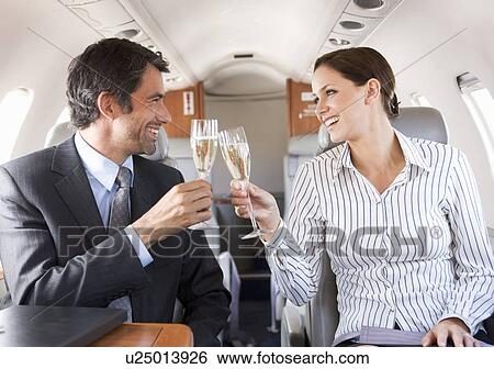 Two business colleagues drinking champagne on a flight View Large Photo Image Stock Photograph - Two business colleagues drinking champagne on a flight. Fotosearch
