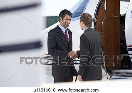 Two business colleagues shaking hands before departure View Large Photo Image Stock Photo - Two business colleagues shaking hands before departure. Fotosearch