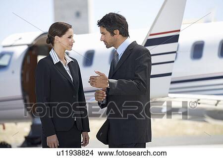 Picture - Two business colleagues standing by a plane. Fotosearch