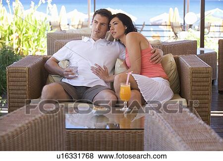 A couple relaxing with a drink on holiday View Large Photo Image Stock Photo - A couple relaxing with a drink on holiday. Fotosearch