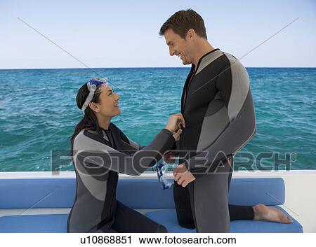 Stock Image - A couple on a boat preparing to go scuba diving. Fotosearch