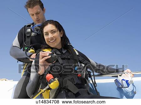Stock Photo - A couple on a boat preparing to go scuba diving. Fotosearch