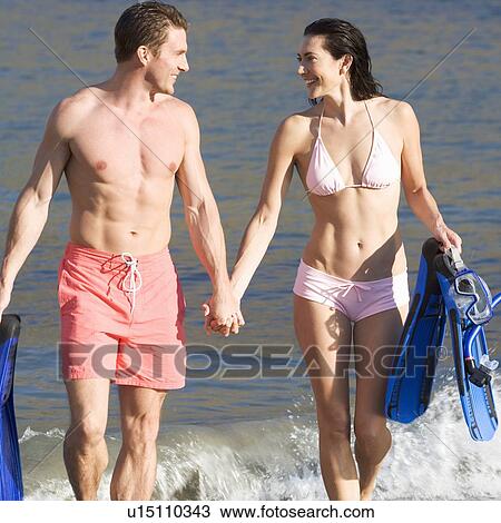 Stock Image - A couple walking on a beach. Fotosearch