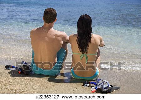 A couple sitting on a beach on holiday View Large Photo Image Stock Photo - A couple sitting on a beach on holiday. Fotosearch