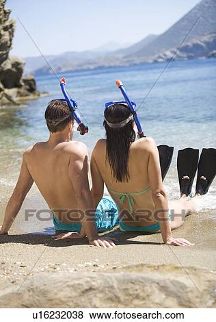 A couple wearing snorkeling equipment sitting on a beach View Large Photo Image Stock Photo - A couple wearing snorkeling equipment sitting on a beach. Fotosearch
