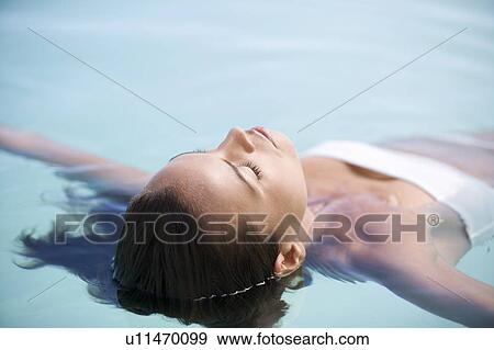 A woman floating in a pool View Large Photo Image Stock Photo - A woman floating in a pool. Fotosearch