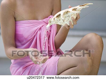 A young woman holding a shell View Large Photo Image Stock Photo - A young woman holding a shell. Fotosearch