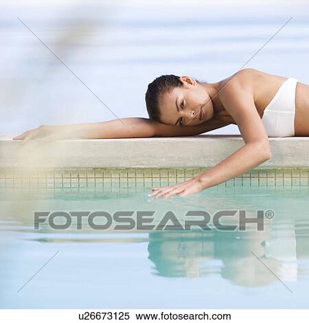 Stock Photography - A young woman laying by a pool. Fotosearch