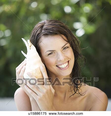 A young woman listening to a sea shell View Large Photo Image Stock Photography - A young woman listening to a sea shell. Fotosearch