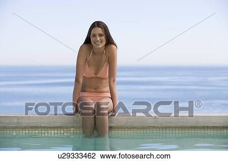A young woman sitting on the edge of a pool View Large Photo Image Stock Image - A young woman sitting on the edge of a pool. Fotosearch