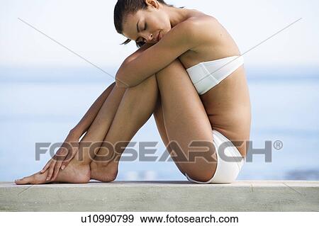 A young woman sitting on the edge of a pool View Large Photo Image Stock Photo - A young woman sitting on the edge of a pool. Fotosearch