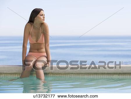 A young woman sitting on the edge of a pool View Large Photo Image Stock Photo - A young woman sitting on the edge of a pool. Fotosearch