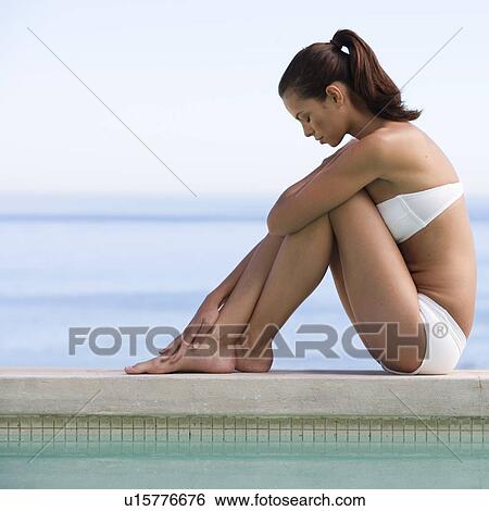 A young woman sitting on the edge of a pool View Large Photo Image Stock Photograph - A young woman sitting on the edge of a pool. Fotosearch