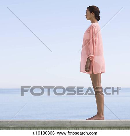 Stock Image - A young woman standing by the edge of a pool. Fotosearch