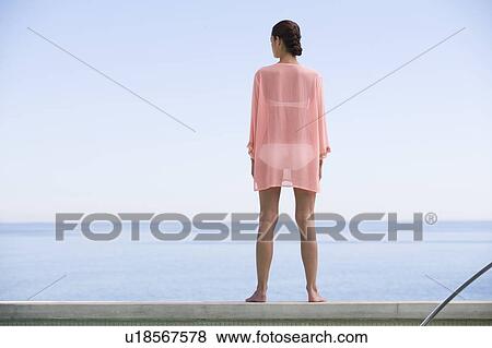 Stock Photo - A young woman standing by the edge of a pool. Fotosearch