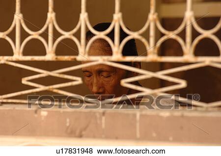 Stock Photo - Burmese man praying behind fence. Fotosearch