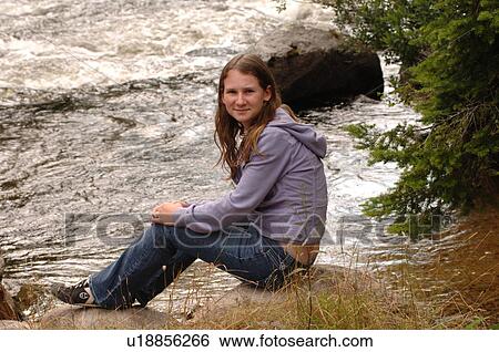 Girl sitting at edge of river View Large Photo Image Stock Photograph - Girl sitting at edge of river. Fotosearch