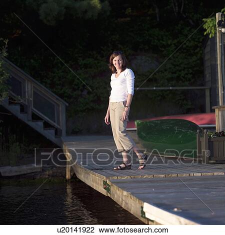 Portrait of a young woman standing on a pier View Large Photo Image Stock Image - Portrait of a young woman standing on a pier. Fotosearch