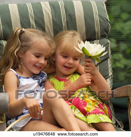 Two young girls sitting in a chair holding a lotus View Large Photo Image Stock Photo - Two young girls sitting in a chair holding a lotus. Fotosearch