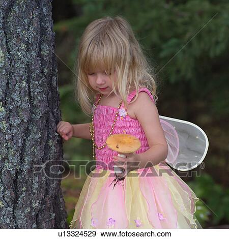 Young girl in a fairy costume standing by a tree View Large Photo Image Stock Photo - Young girl in a fairy costume standing by a tree. Fotosearch