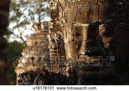 Stock Image - Stone carving of a face on wall at Khmer Kingdom palace ruins. Fotosearch