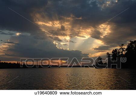 Stock Photo - Sunlight through clouds at twilight. Fotosearch