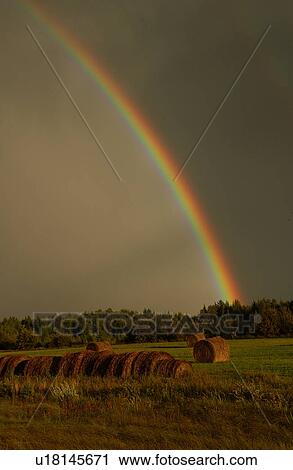 Stock Image - View of a rainbow over a farm. Fotosearch