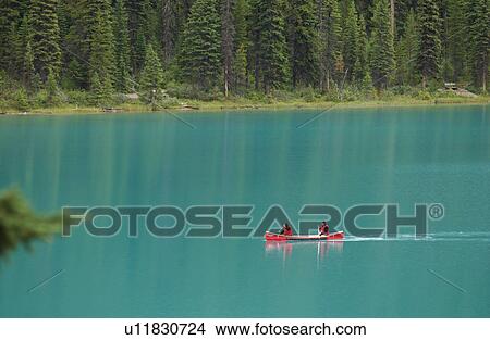 Picture - A couple in a boat on a lake between mountains, Rocky Mountains, Canada. Fotosearch