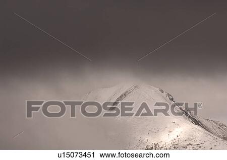 Stock Image - Cloud over Top of Snow Capped Mountain Peak, Jasper National Park, Canada. Fotosearch