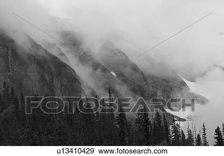 Stock Photo - Fog enveloping a mountain, Rocky Mountains, Canada. Fotosearch