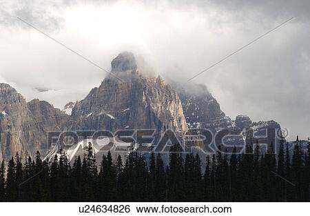 Panoramic view of a mountain peak enveloped in clouds, Rocky Mountains, Canada View Large Photo Image Stock Photograph - Panoramic view of a mountain peak enveloped in clouds, Rocky Mountains, Canada. Fotosearch
