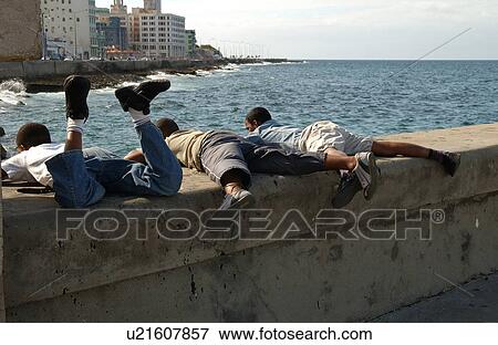 Three people lying on a wall facing the ocean, Havana, Cuba View Large Photo Image Stock Photo - Three people lying on a wall facing the ocean, Havana, Cuba. Fotosearch