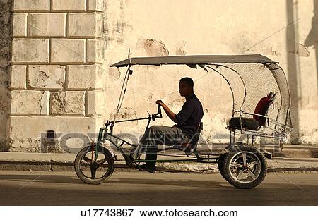 Stock Photo - Side profile of a young man driving a Pedicab, Havana, Cuba. Fotosearch