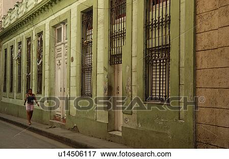 Stock Photo - Young woman walking on the sidewalk of a street, Havana, Cuba. Fotosearch
