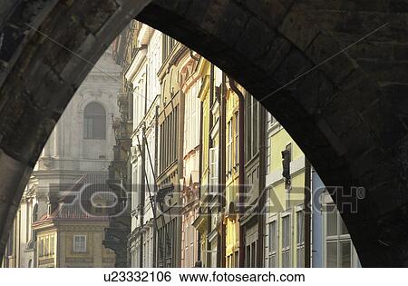 Stock Photograph - Ancient historical buildings seen through an arch way in Prague. Fotosearch