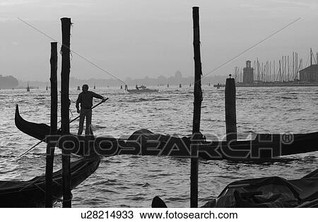 Stock Image - Oarsman driving a gondola in a canal in Venice, Italy. Fotosearch