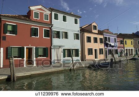 Stock Photograph - An array of colorful residential buildings along a canal in Venice, Burano, Italy. Fotosearch