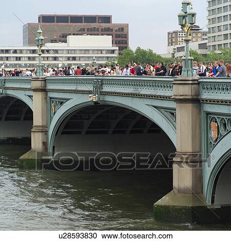 Stock Image - Group of people walking on a bridge, London, England. Fotosearch
