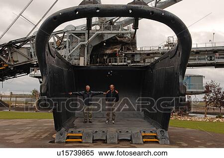 Stock Photography - Two men standing inside a scoop. Fotosearch
