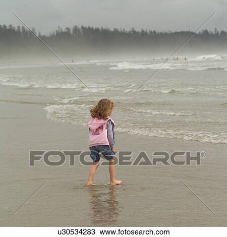Stock Image - Girl standing in water on beach, Pacific Rim Park, Vancouver Island, Canada. Fotosearch