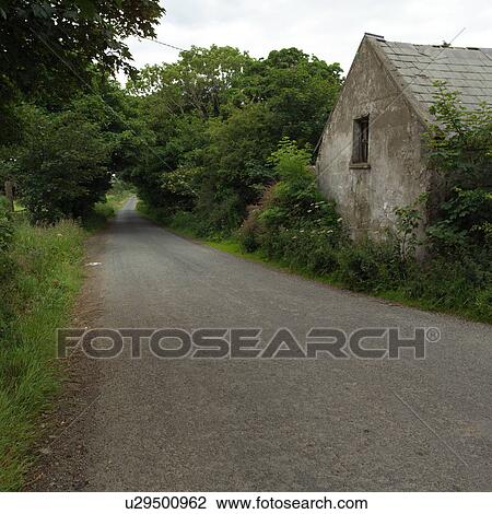 Stock Image - Ireland - countryside road with house. Fotosearch