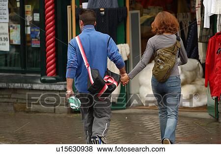 Stock Photo - Rear view of a young couple holding hands and walking. Fotosearch